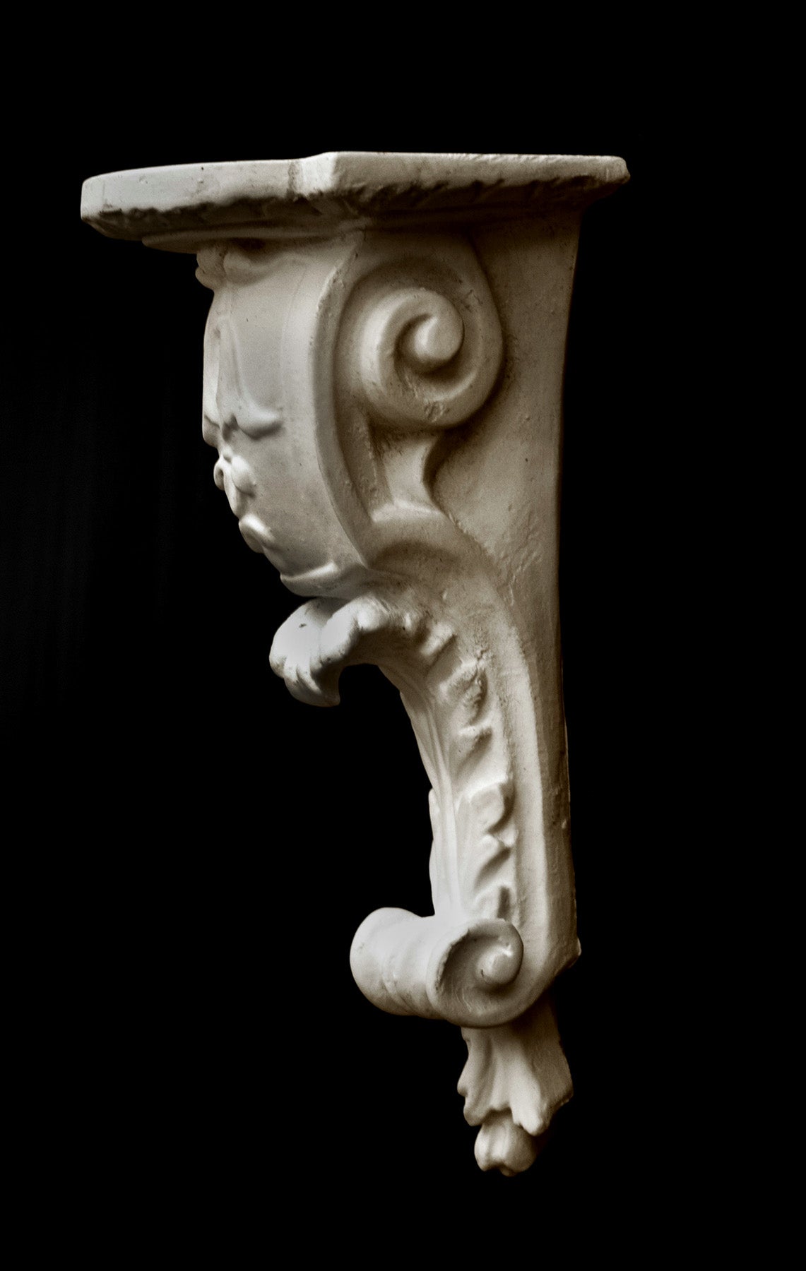 image of a plaster statue of a renaissance bracket on a black background