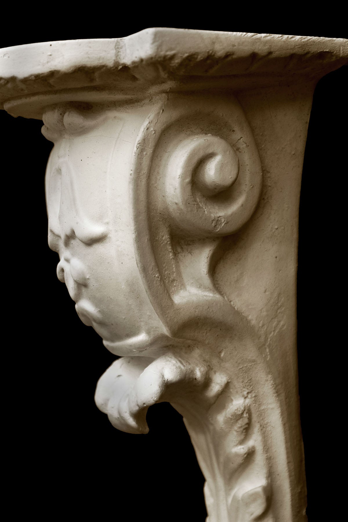 image of a plaster statue of a renaissance bracket on a black background