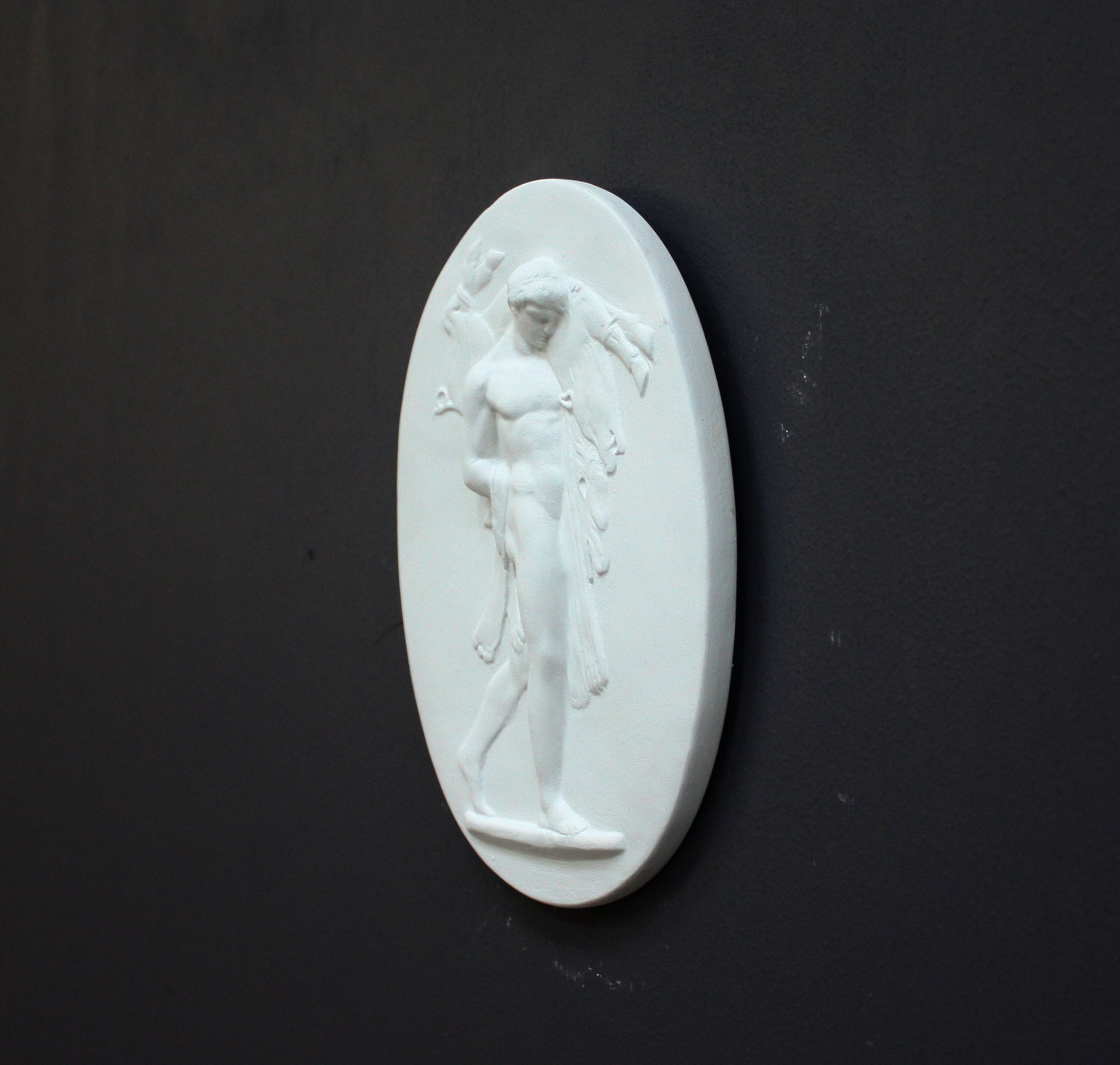 Image of a small plaster plaque of Hercules carrying a boar on a black background