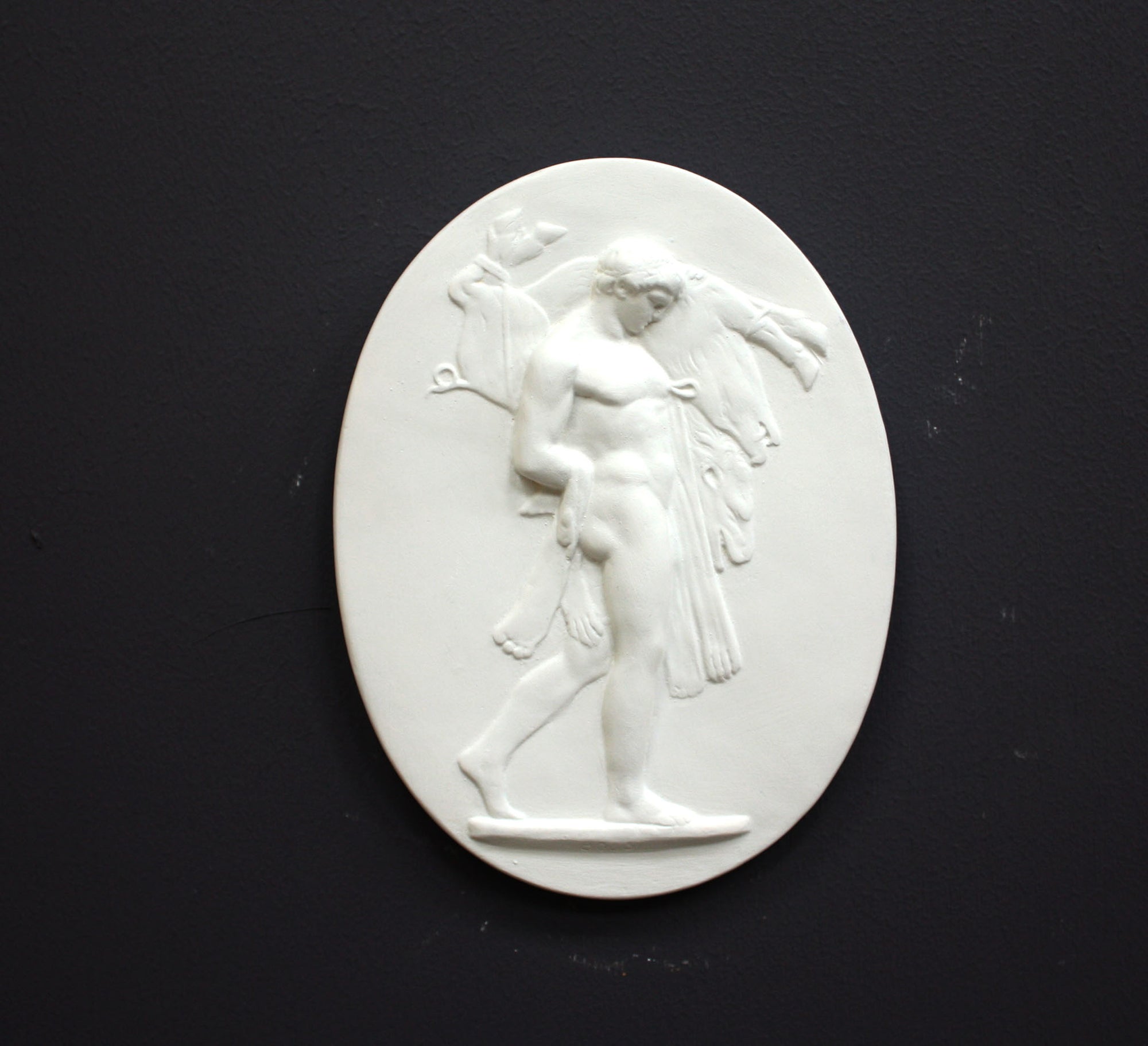 Image of a small plaster plaque of Hercules carrying a boar on a black background