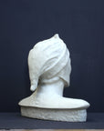 photo of plaster cast bust sculpture of Dante Alighieri with cap and high-necked robe with red book leaning against right side on black background