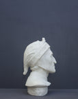 photo of plaster cast bust sculpture of Dante Alighieri with cap and high-necked robe with red book leaning against right side on black background