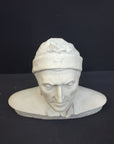 photo of plaster cast bust sculpture of Dante Alighieri with cap and high-necked robe with red book leaning against right side on black background 