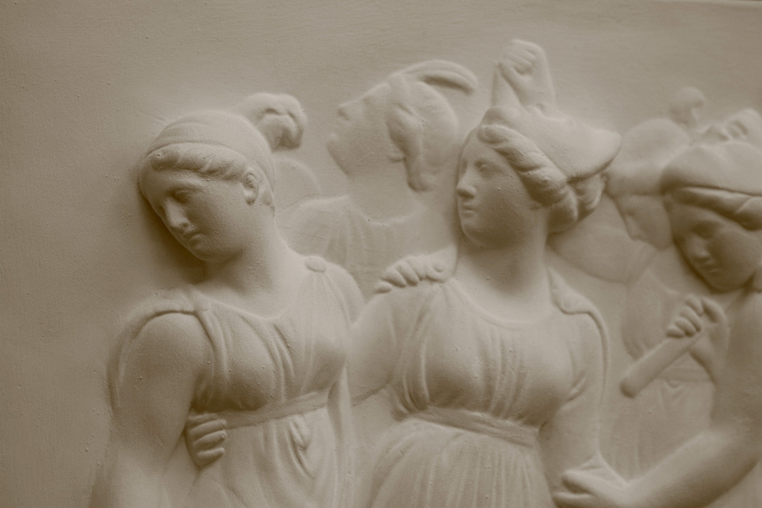 Close up Photo with black background of plaster cast sculpture relief of females dancing
