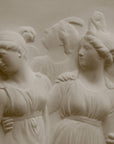 Close up Photo with black background of plaster cast sculpture relief of females dancing
