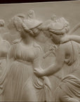 Photo with black background of plaster cast sculpture relief of females dancing
