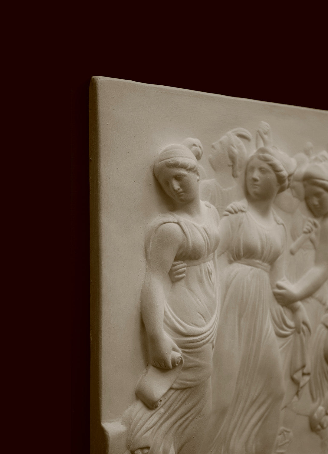 Photo with black background of plaster cast sculpture relief of females dancing