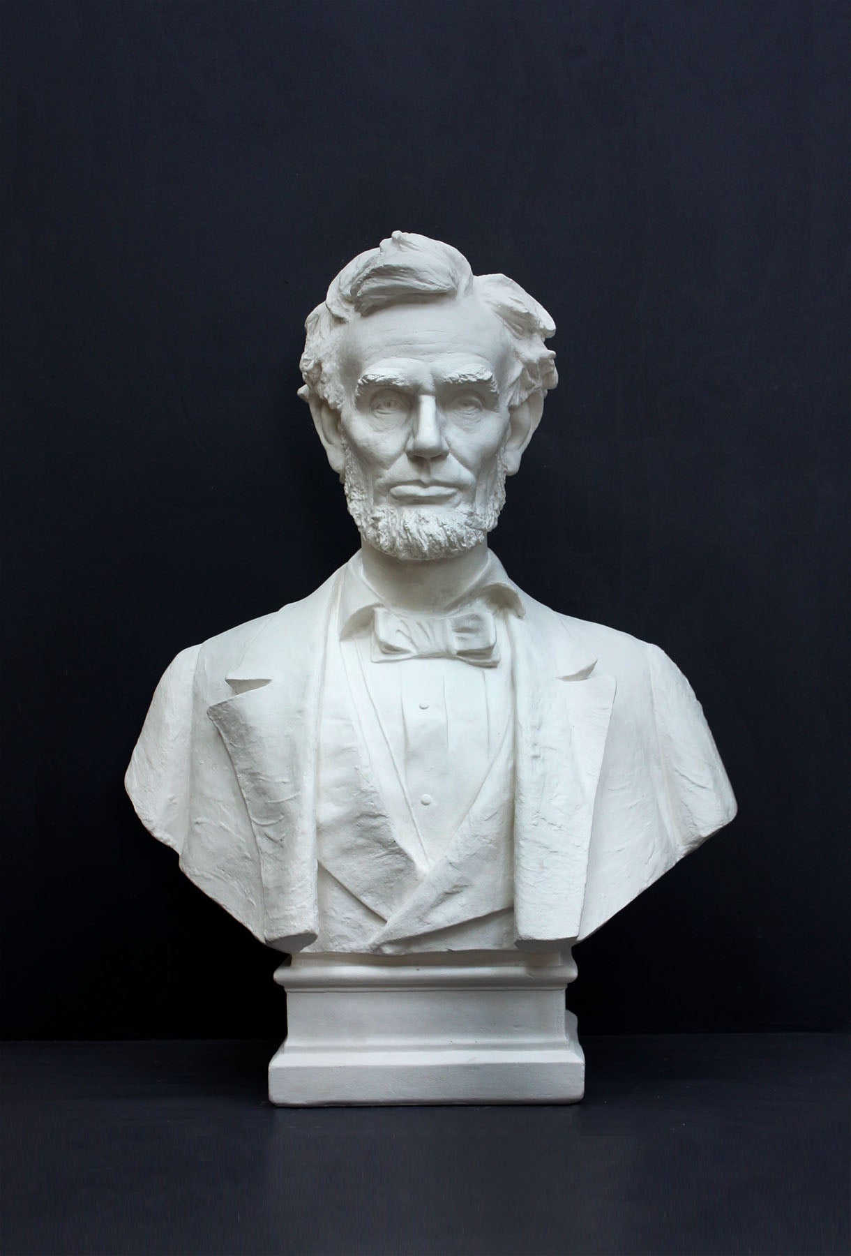 image of a plaster statue of a bust of lincoln on a gray background