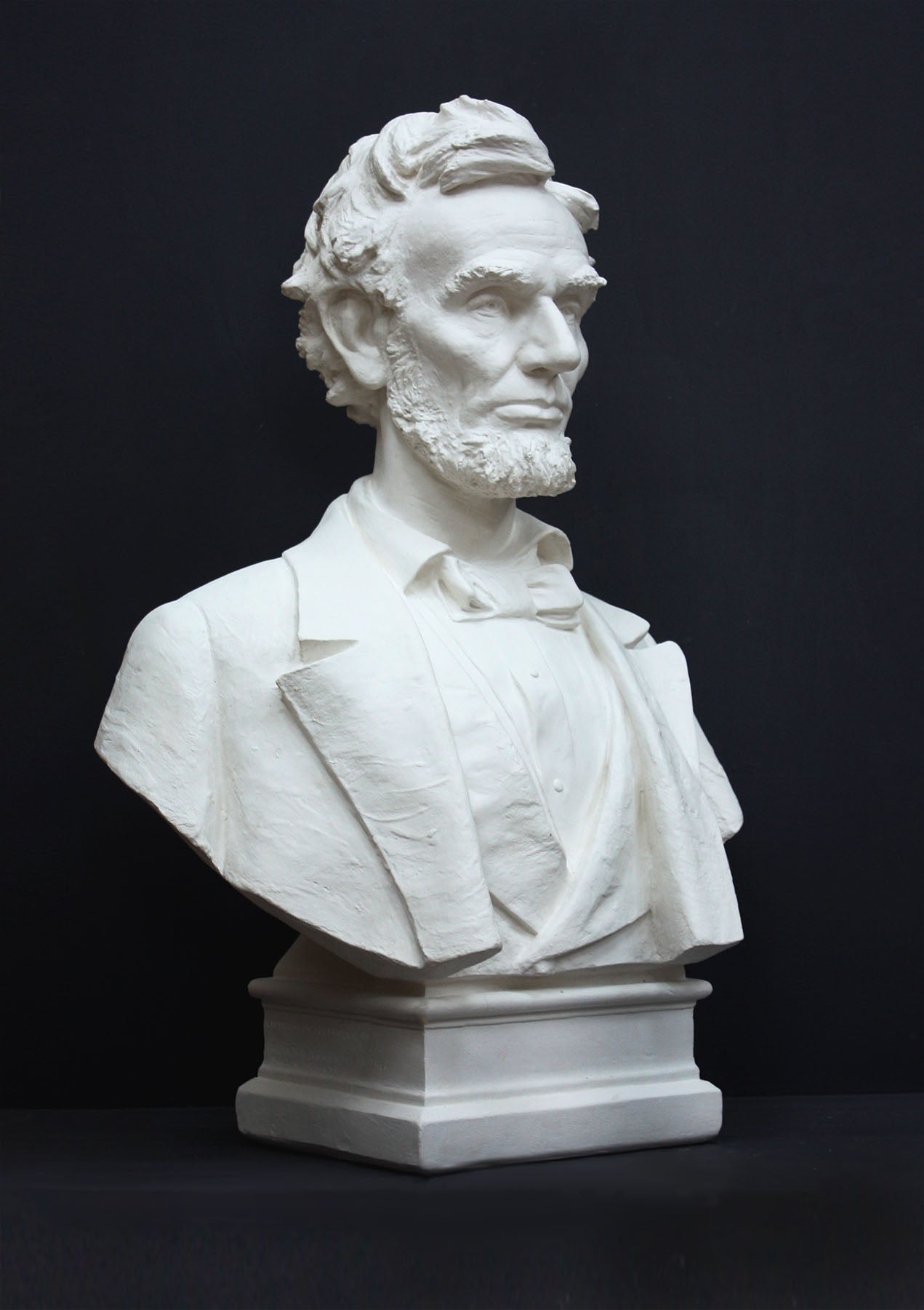 image of a plaster statue of a bust of lincoln on a gray background