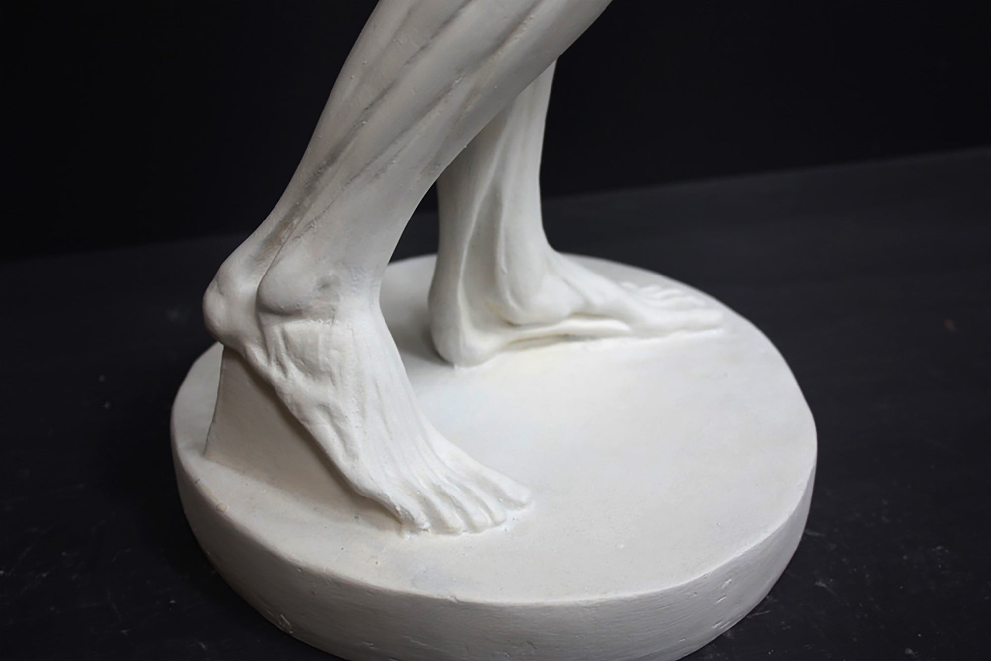 photo of plaster cast sculpture of flayed male figure study with right arm outstretched and left arm down on a gray background