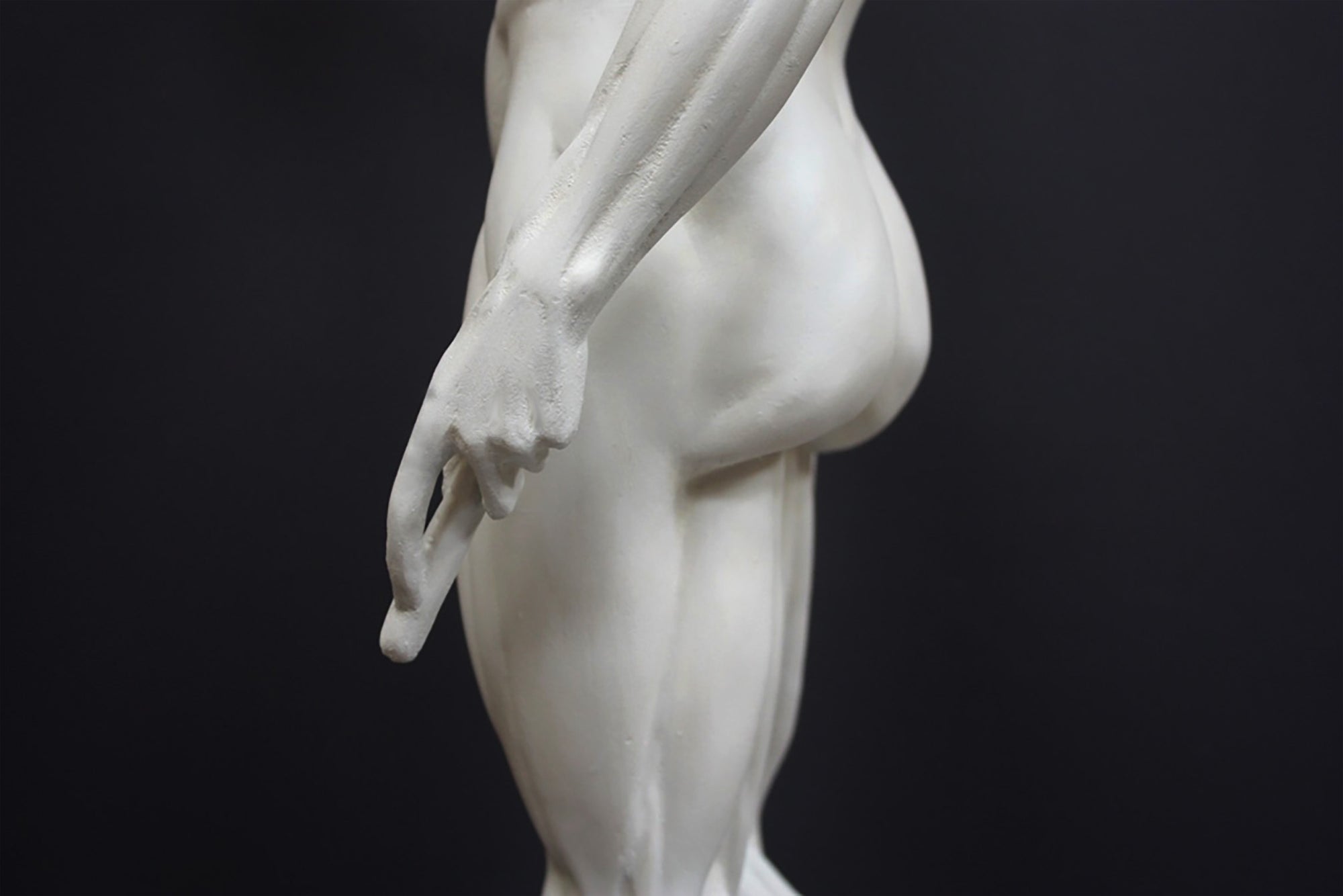 photo of plaster cast sculpture of flayed male figure study with right arm outstretched and left arm down on a gray background