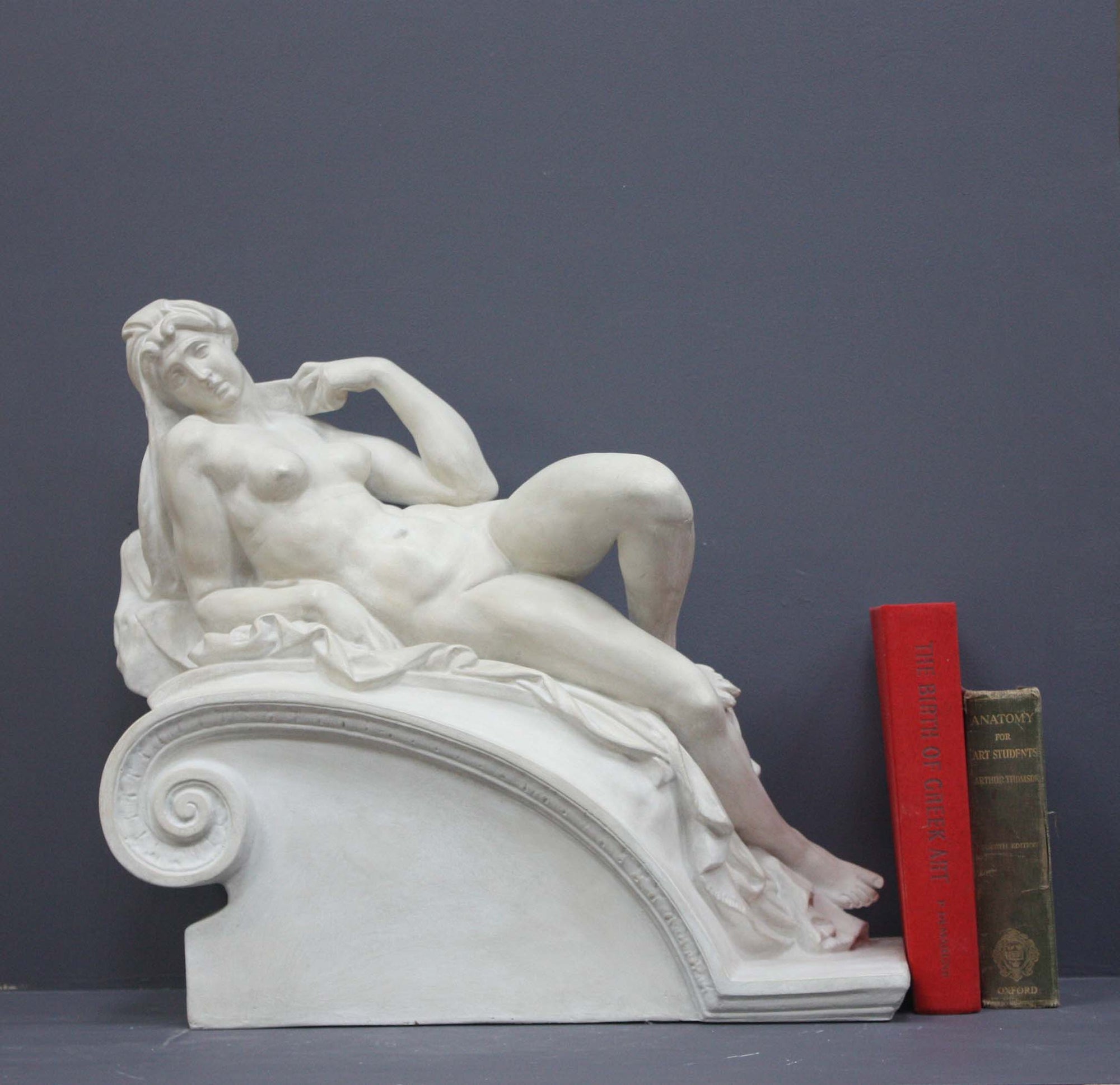 photo of a sculpture of a reclining nude female on a grey background