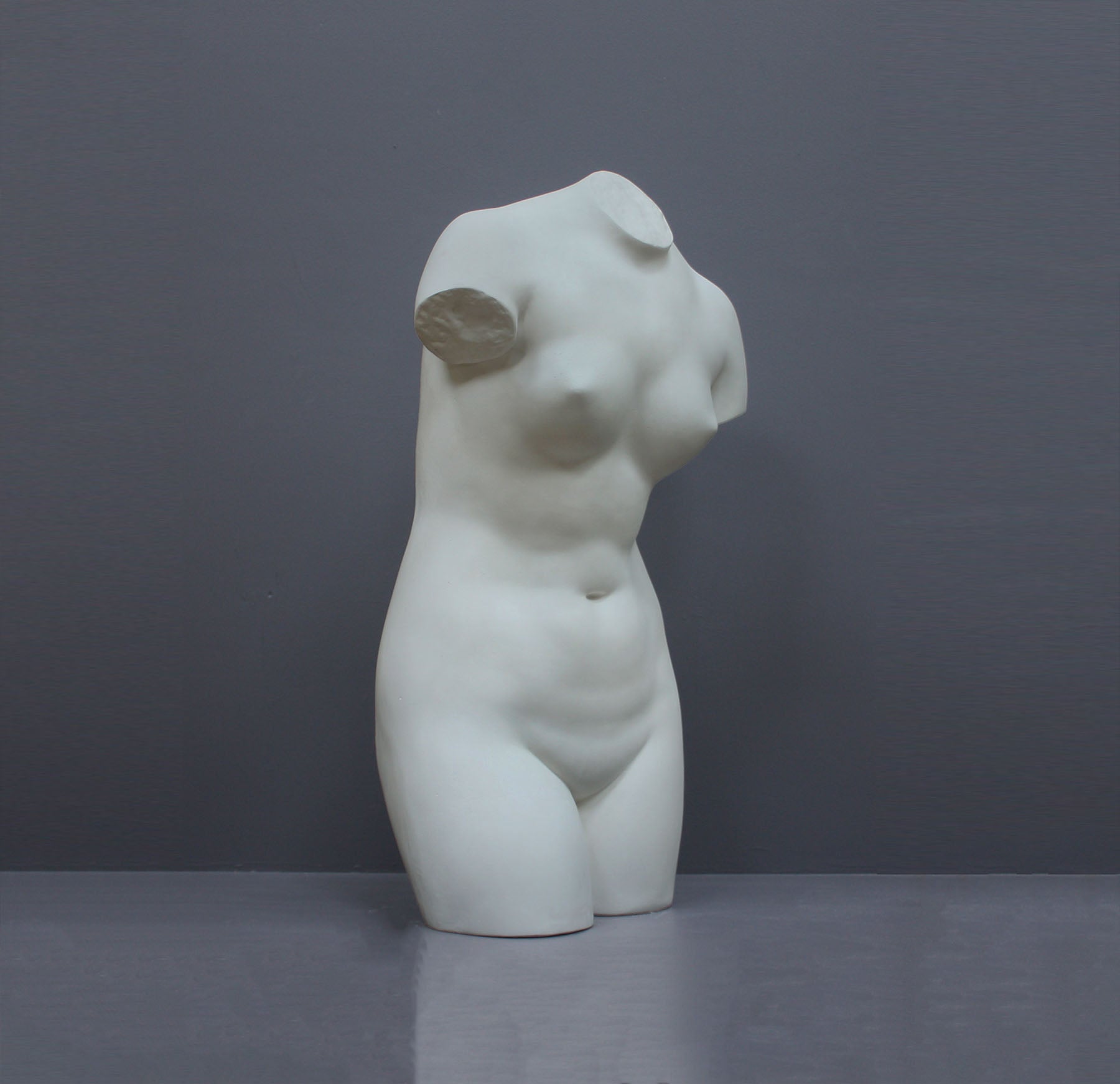 Image of a plaster statue as a bust of venus on a grey background