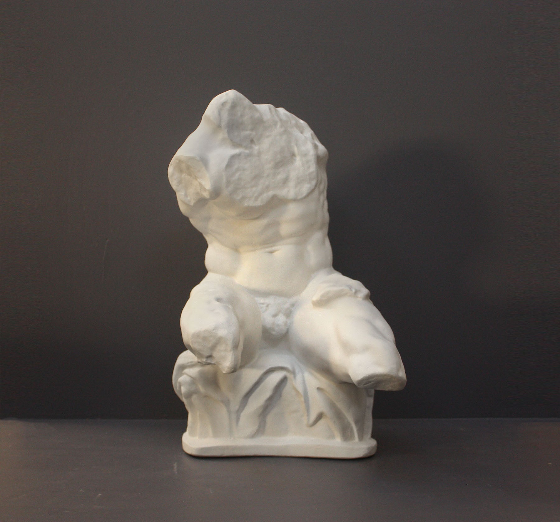 image of a plaster statue of a bust of a belvedere torso on a gray background