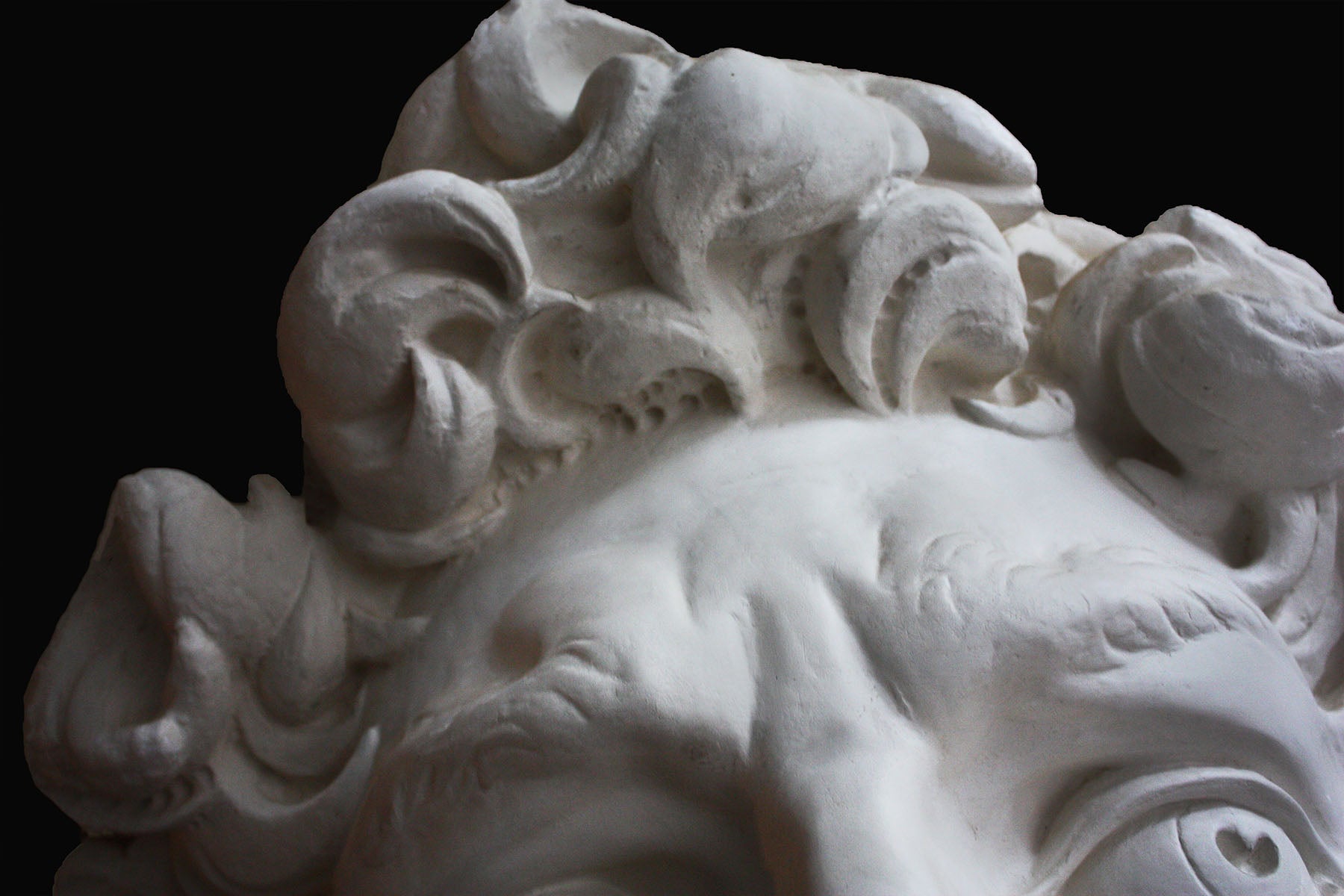 detailed image of a plaster statue of a bust of david on a black background