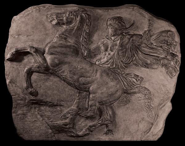 photo of off-white plaster cast relief sculpture of man on horseback from Parthenon against black background