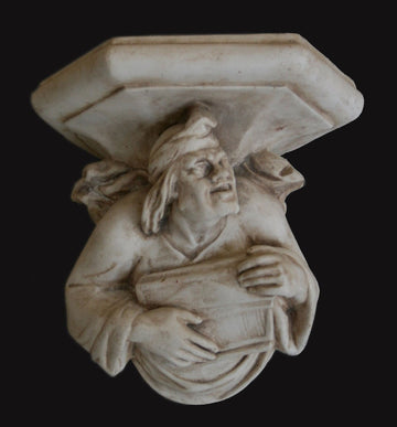 photo with black background of plaster cast sculpture of architectural bracket with a man's upper body who holds a musical instrument