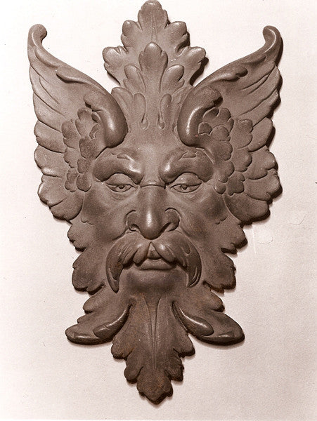 photo of bronze-colored plaster cast sculpture relief of moustached man's face made of leaves with white background