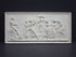 Photo of plaster cast sculpture relief of nude and clothed females (muses) dancing and playing instruments and one male (Apollo) playing a lyre on a dark gray background