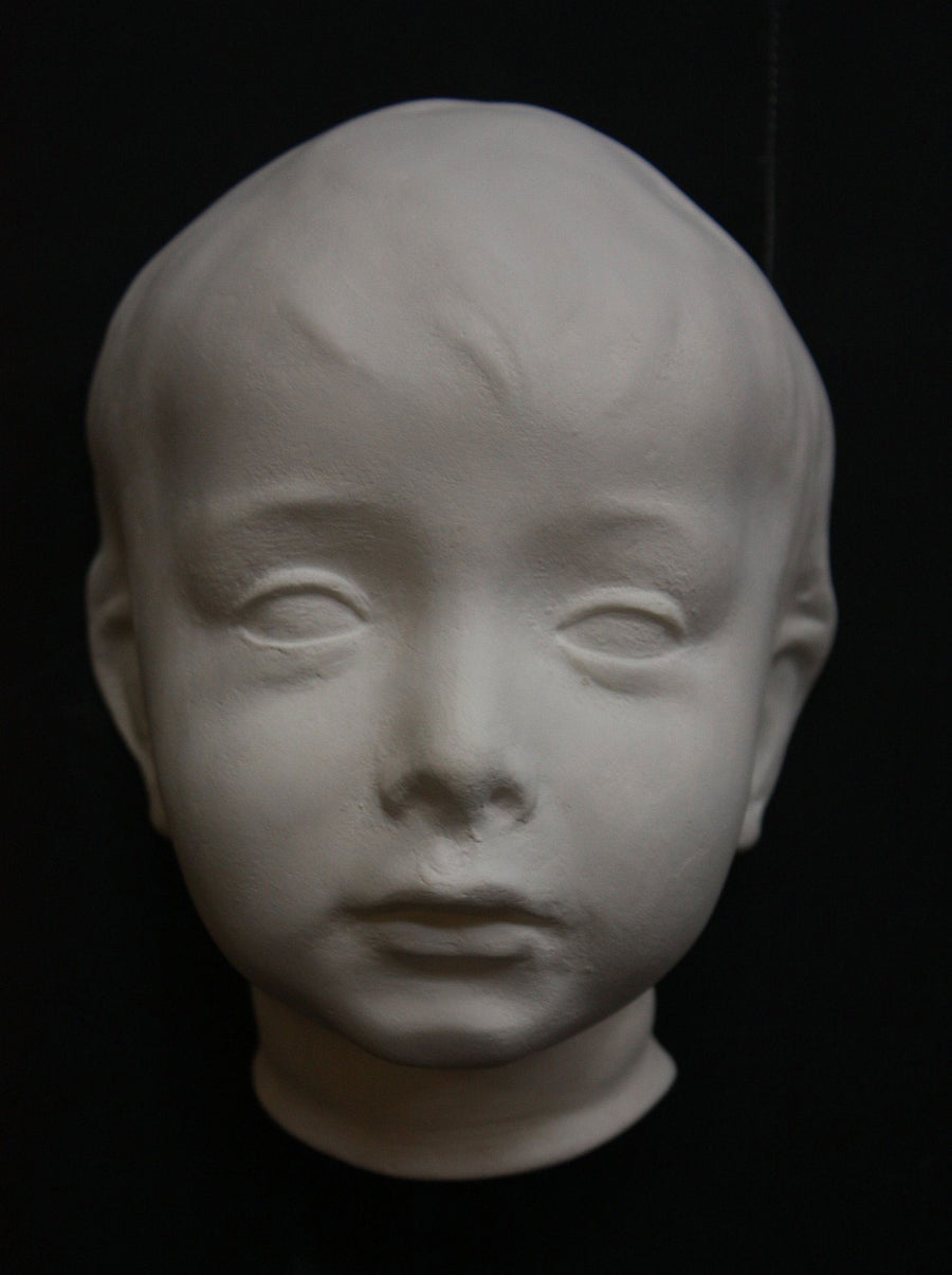 photo with black background of plaster cast sculpture of child's face