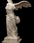 photo of plaster cast sculpture of winged, headless female figure with flowing drapery on top of a Doric-column pedestal on a black background
