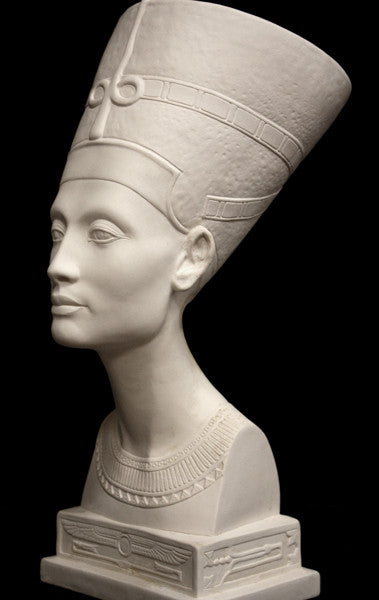photo of plaster cast sculpture of bust of Nefertiti with crown and decorative collar on a decorative base with a black background