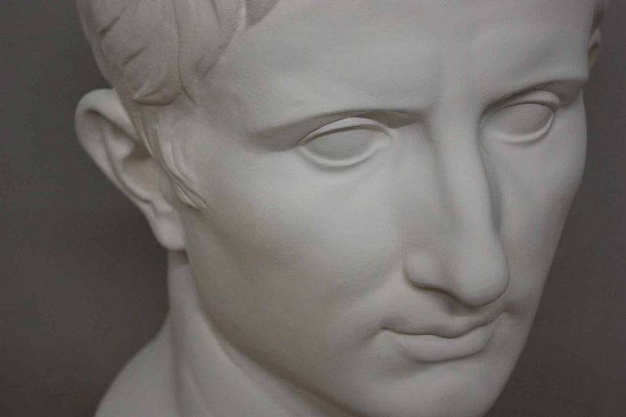 closeup photo of plaster cast bust of man, namely Augustus Caesar, with gray background