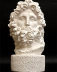 Photo with black background of plaster cast sculpture of male bust, namely the god Zeus, with curly hair and beard