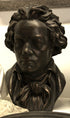 photo of bronze-colored plaster cast sculpture bust of man, namely Beethoven, with neckerchief on light-colored background