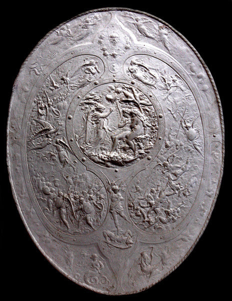 photo of white plaster reproduction of a shield with intricate relief sculpture set against black background