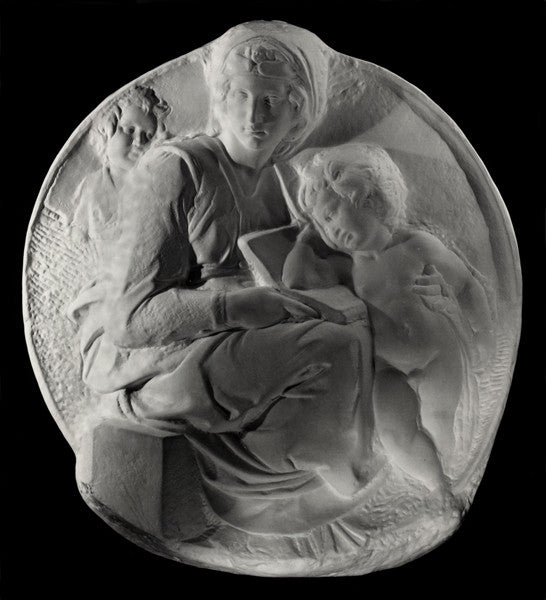 photo of plaster cast sculpture relief of the Madonna sitting with the baby Jesus beside her leaning on a book on her lap on a black background