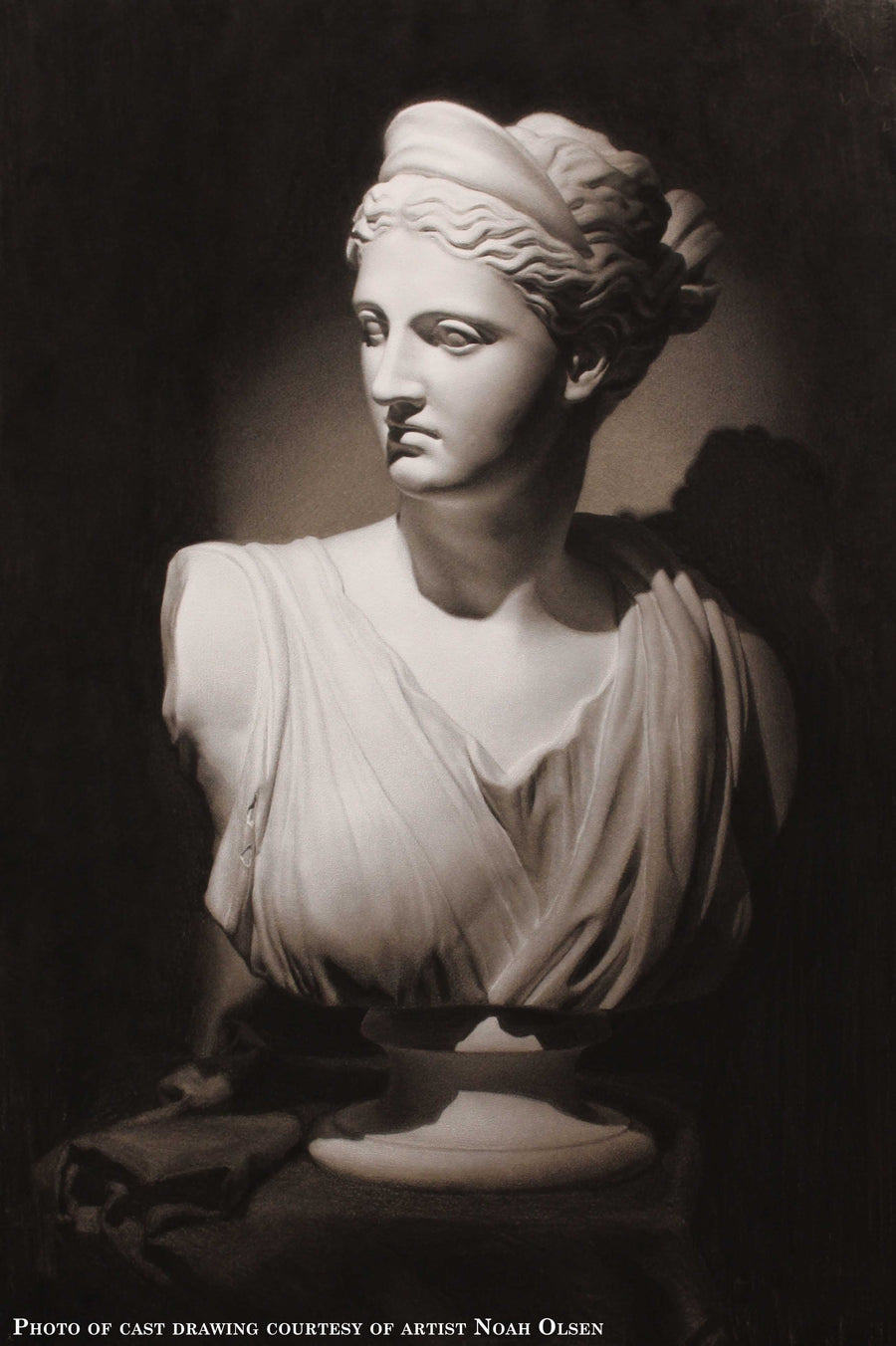 Photo of Cast Drawing of Plaster Caproni Cast of female bust on a table with a cloth over it and rolled into folds beside the statue with a black background