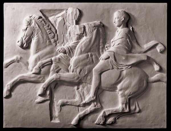 photo of off-white plaster cast relief sculpture of two men on horseback from Parthenon against black background