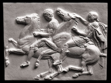 photo of off-white plaster cast relief sculpture of two men on horseback from Parthenon against black background