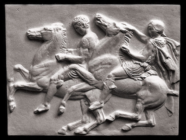 photo of off-white plaster cast relief sculpture of two men on horseback from Parthenon against black background