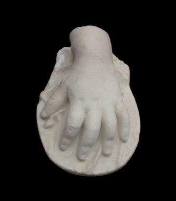 photo of white plaster cast sculpture of baby hand against black background