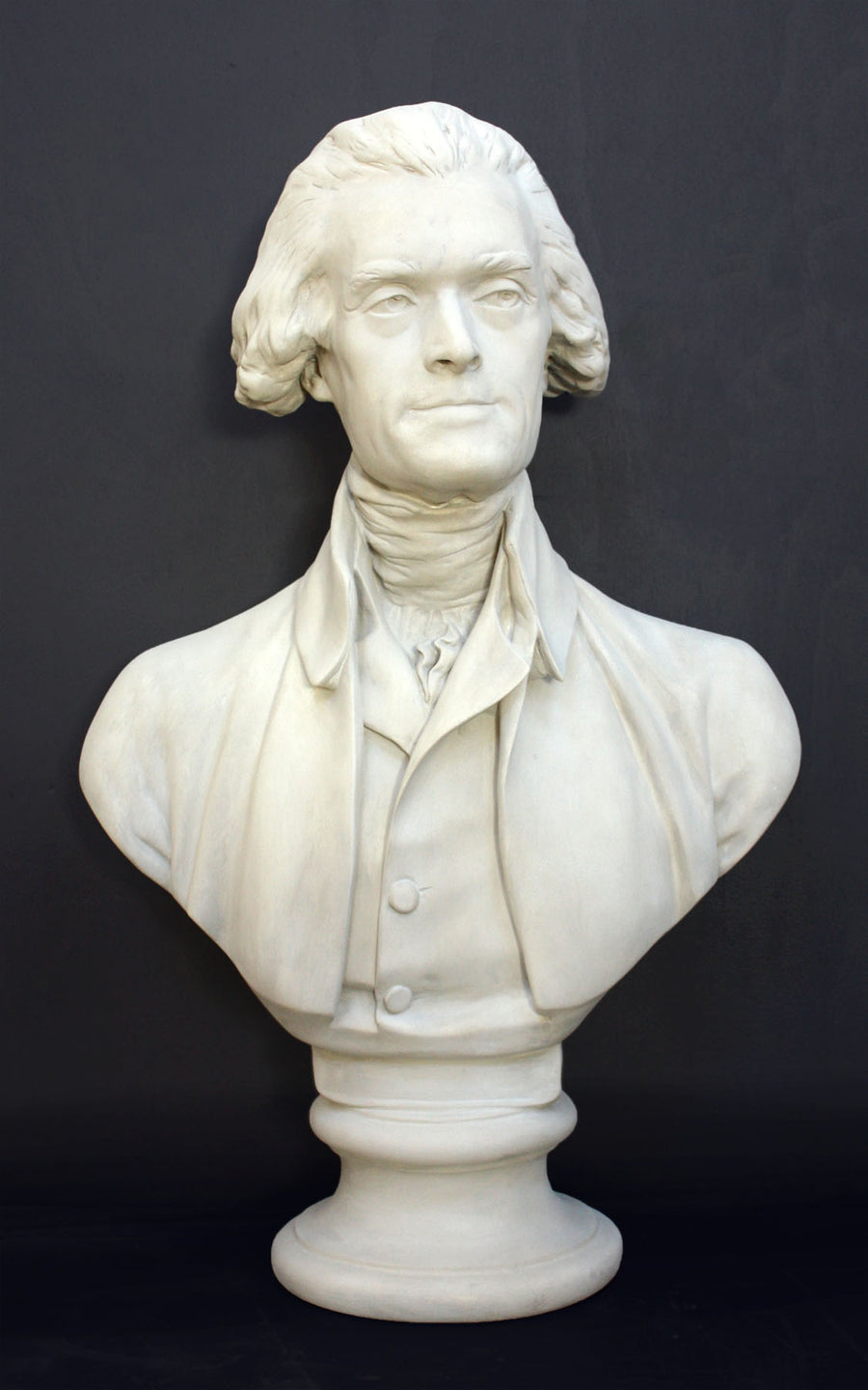 Photo of plaster cast bust sculpture of man with coat and neckerchief, namely Thomas Jefferson, with dark gray background