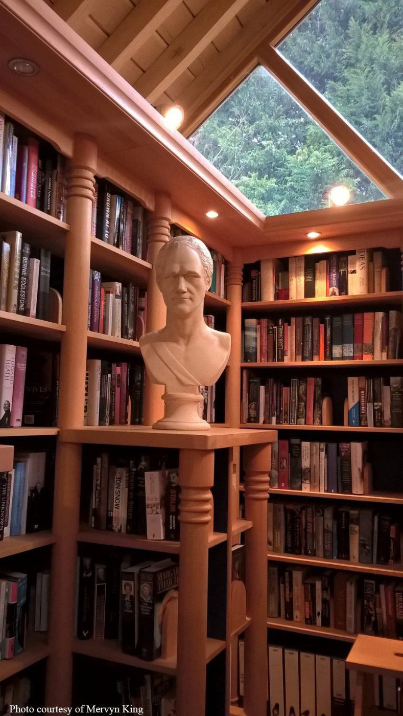 photo of two walls of a library filled with books and skylights in ceiling and plaster cast bust of Alexander Hamilton on table
