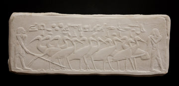 photo of plaster cast relief sculpture of herons and people on a black background