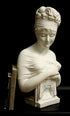 photo with black background of plaster cast sculpture bust of Madame Recamier with high up-do and ribbon over forehead and hands crossed over chest covered in cloth, and two books leaning against her