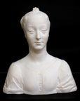 photo of white plaster cast of female bust with up-do and dress against black background