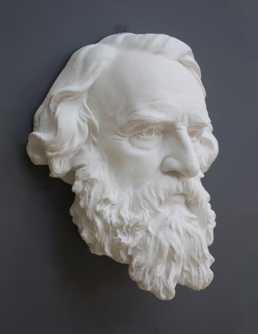photo of plaster cast of man's head, namely Longfellow, with long hair and curly beard on gray background