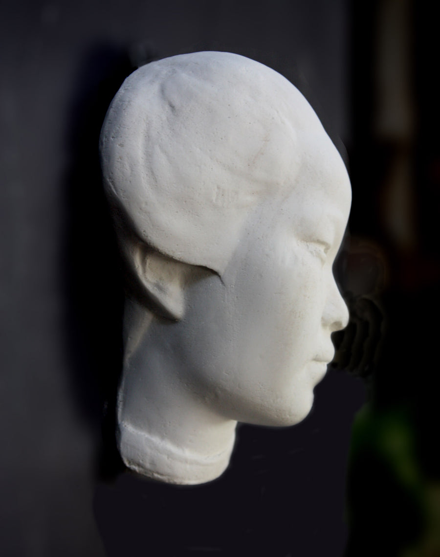 Photo of plaster cast of face of Chinese female, profile view, on a black background