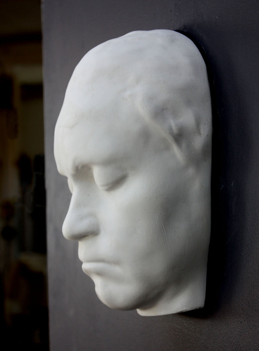 Photo of sculpture of life mask of Beethoven, side view, on a black background