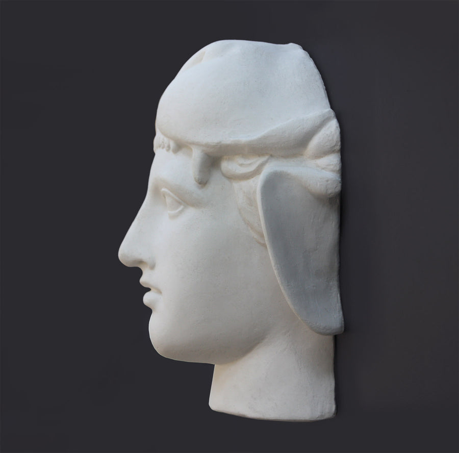 profile photo of white plaster cast of ancient sculpture of head, namely Omphale or Hercules, wearing Nemean lion skin against dark gray background