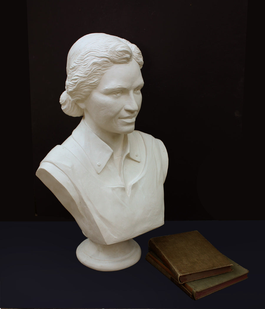 Photo of plaster cast of sculpture bust of Rosa Parks on a black background with two books sitting on the right side