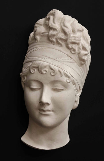photo with black background of plaster cast sculpture of face of Madame Recamier with high up-do and ribbon over forehead
