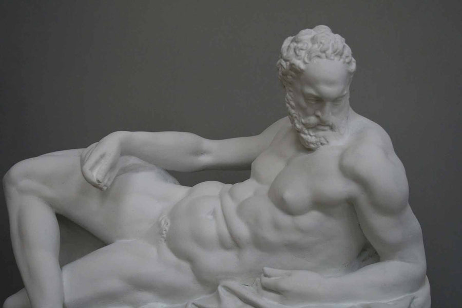 photo of plaster cast of reclining male nude with a gray background