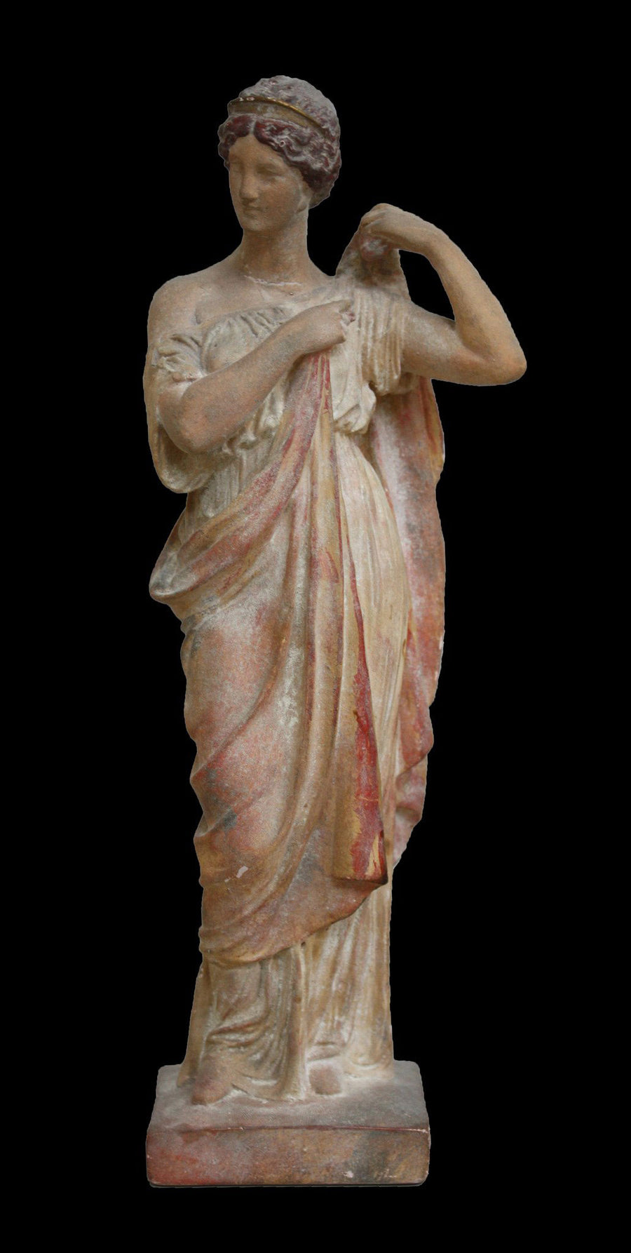 photo of plaster cast statue of female in pink robes with left arm raised  and holding robe against black background