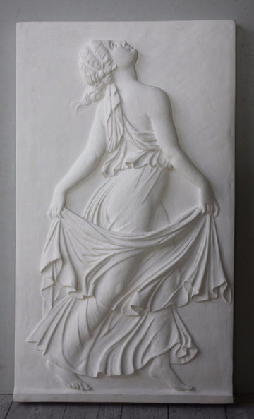 Photo of plaster cast relief of female in robes dancing and swaying more fabric behind her with gray background